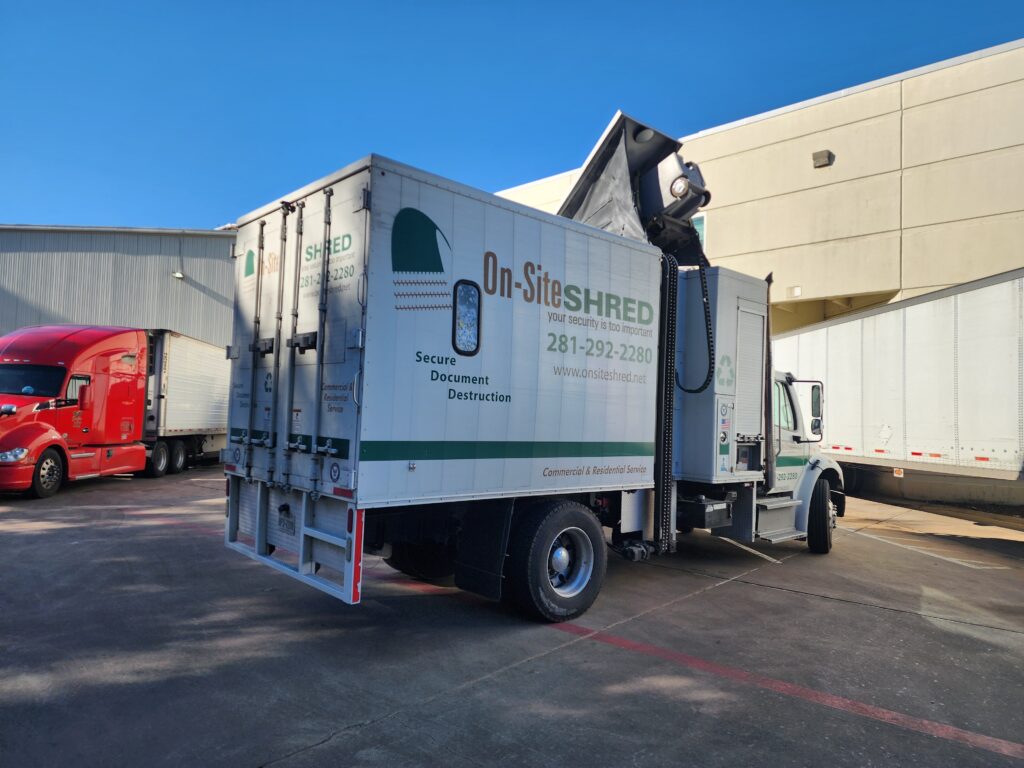 Document shredding truck at warehouse loading area.